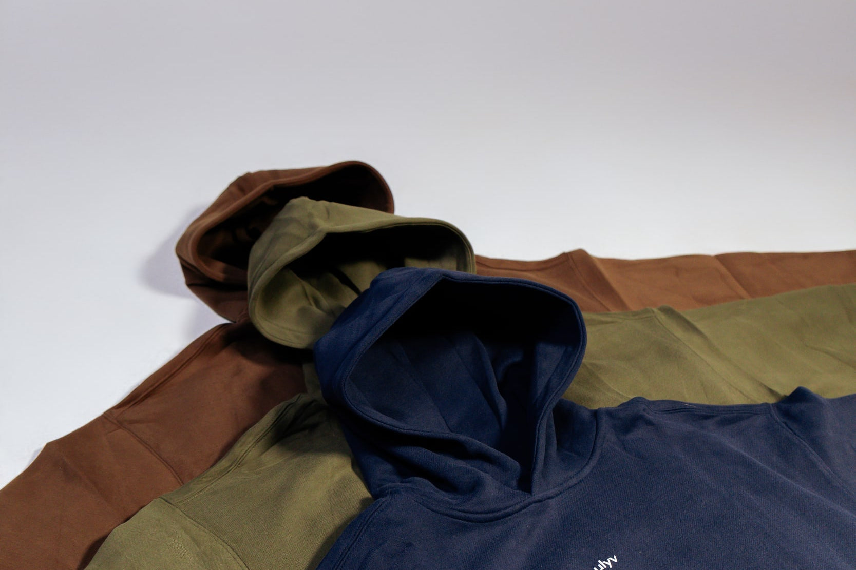 Close view of ULYV essential hoodies in navy olive and brown