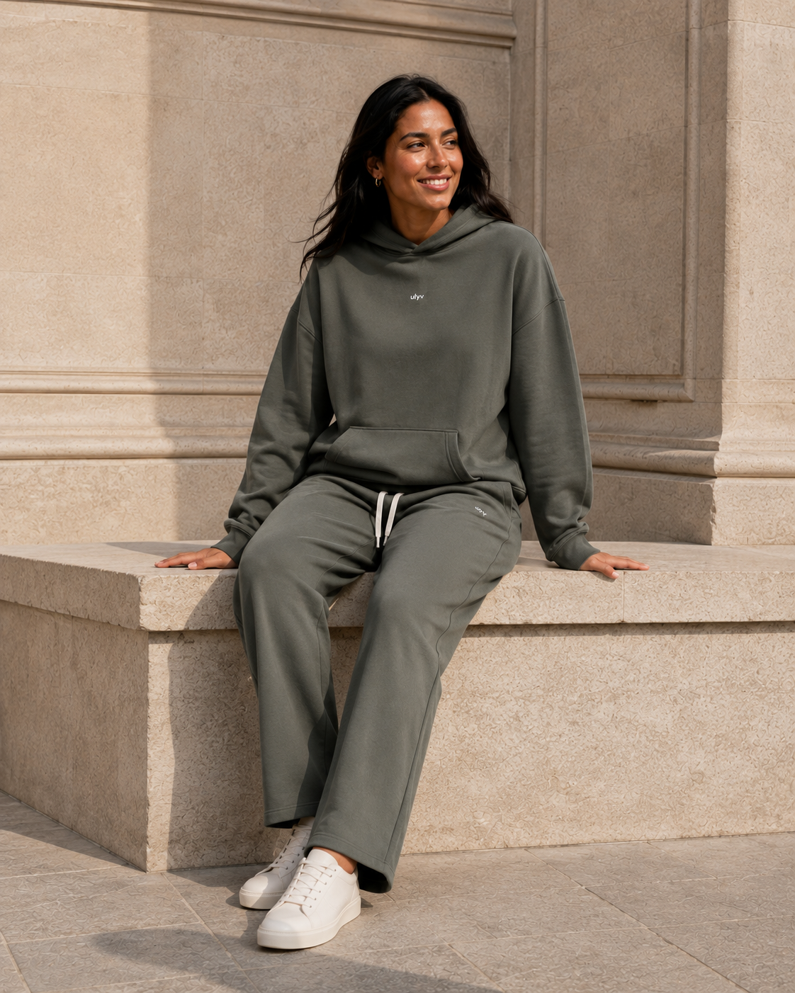 Adult woman wearing the Olive ULYV matching hoodie and sweatpants, full length editorial view