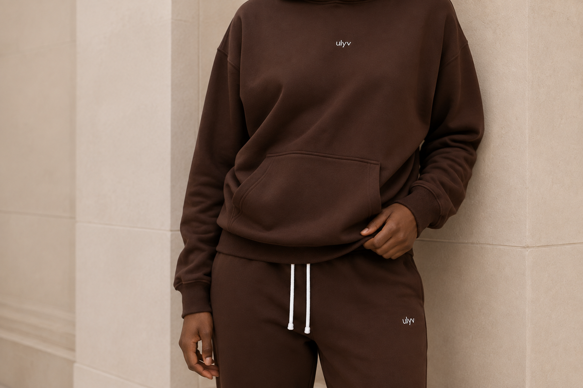 Close view of the Brown ULYV hoodie and sweatpants, showing the kangaroo pocket and small white logos.