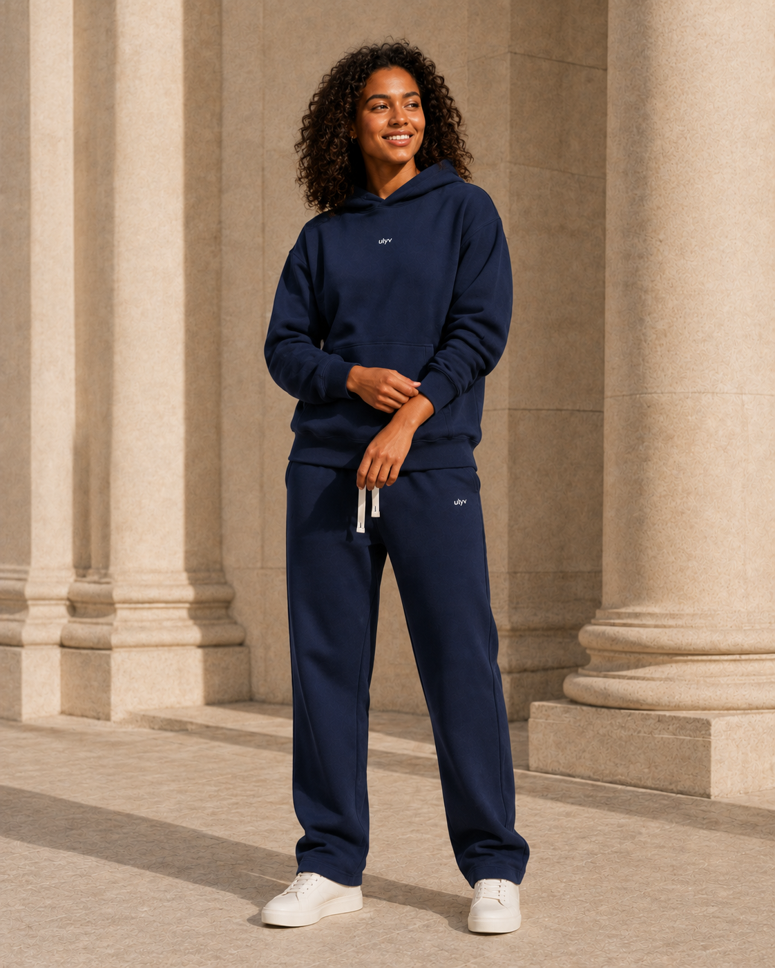 Adult woman wearing the Navy ULYV matching hoodie and sweatpants, full length editorial view