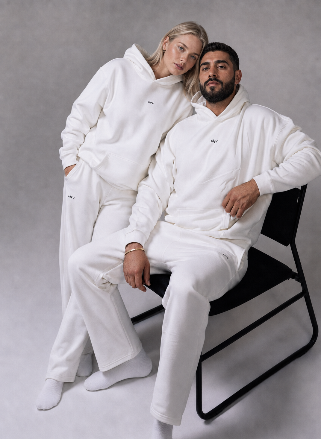 Two adult models wearing matching white ULYV heavyweight cotton sets